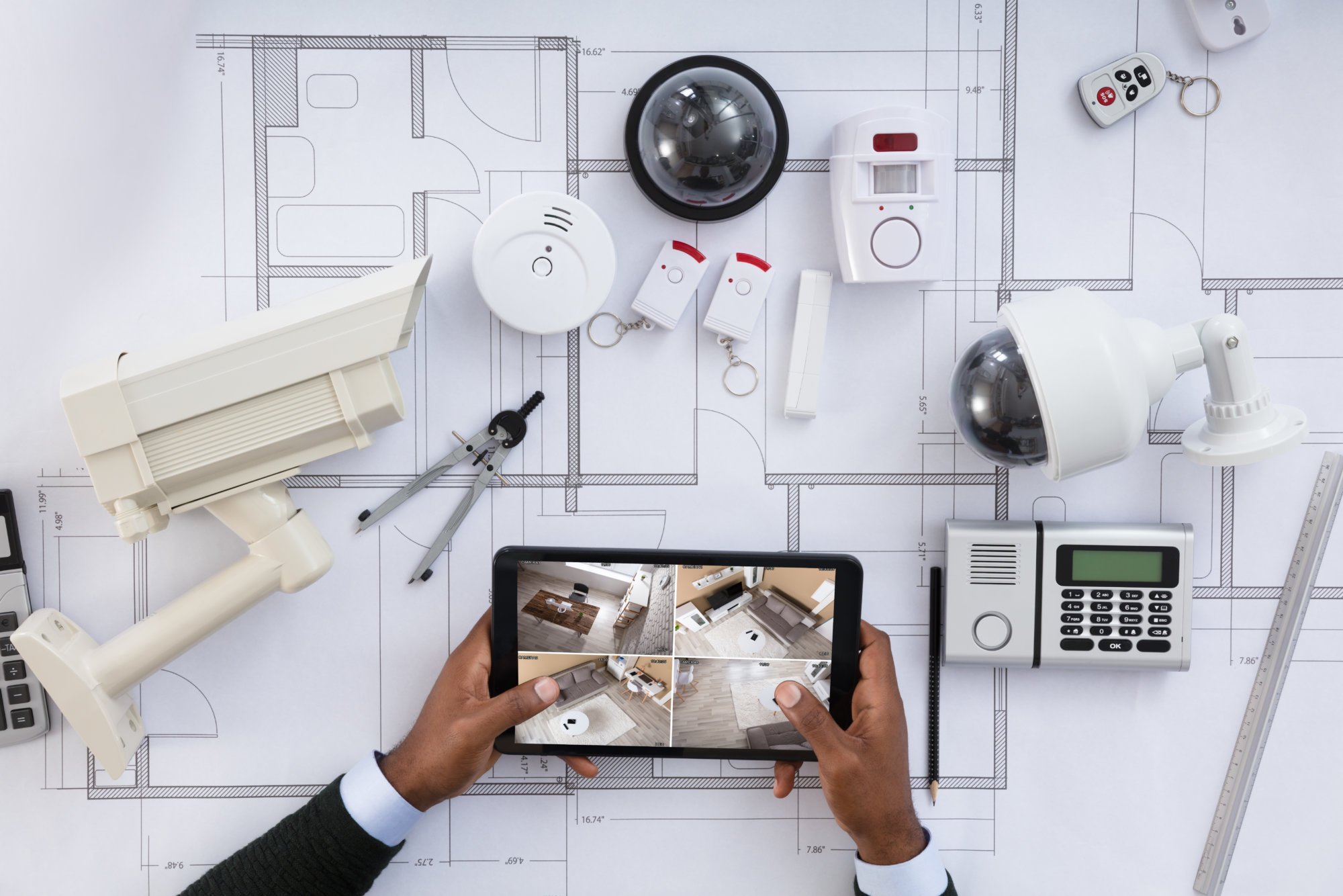 Close-up Of A Person Watching Footage On Digital Tablet With Security Equipments On Blueprint