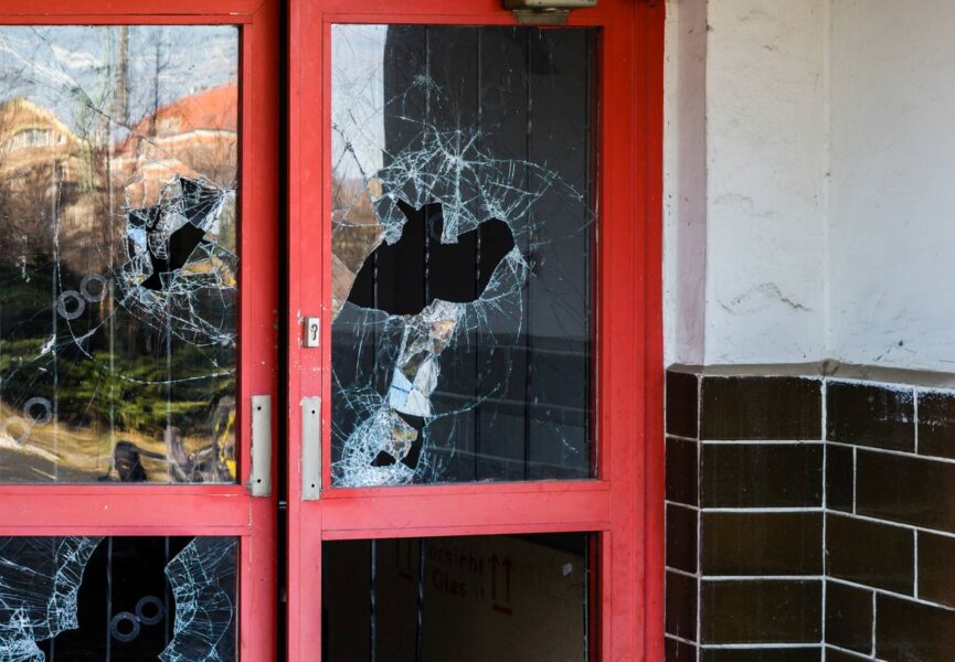 Broken glass on a red door to a business.