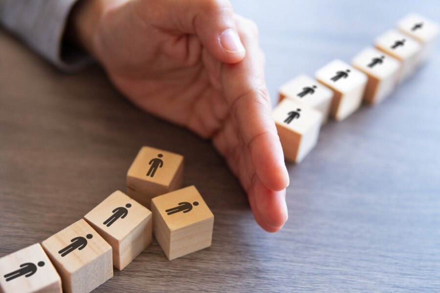 A manager divides wooden blocks on their desk as part of a visualization exercise when firing employees.