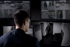Security man monitoring corporate surveillance camera indoors, safety concept